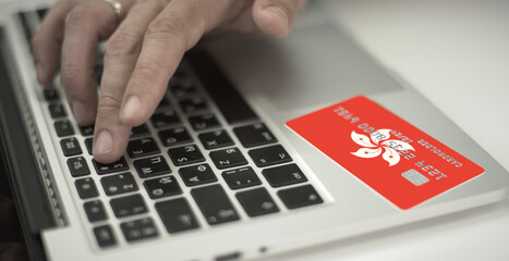 Unknown man pays online with plastic bank card with printed flag of Hong Kong. Fictional numbers