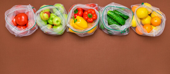 Wide banner Fresh ripe and juicy fruits and vegetables in reusable eco friendly mesh bags on the brown background. Plastic free, zero waste, and sustainable living concept. Reusable using. Copy space.