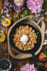 Blueberry and peaches crispy oatmeal crumble with ice cream, wooden table