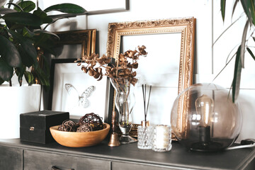 Stylish interior of living room with mock up poster frame, design sofa, wooden cube, pendant lamp, plant, carpet, pillows, plaid, books, clock and elegant personal accessories in modern home decor