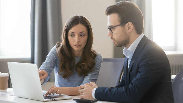Young businesswoman manager consulting client, confident businessman, coach teaching intern, using laptop, helping with corporate software, colleagues working on project together, horizontal photo