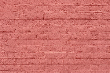 Red brick wall, background with copy space. Old bricks covered with colored red plaster, texture background. Renovation and decoration of old surface