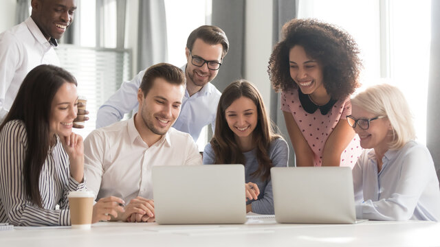 Happy smiling diverse employees using laptop, watching webinar together, engaged in online conference, students, office workers working on project, teamwork concept, horizontal photo