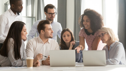 Diverse employees team discussing online project at briefing, listening to mixed race businesswoman sharing startup ideas, using laptop at office meeting, teamwork concept, horizontal photo