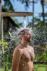 Young handsome man bathing under an outdoor shower. Summer lifestyle