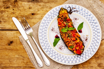 Karniyarik traditional Turkish food from stuffed eggplants with minced meat, tomato, greens and sesame seeds