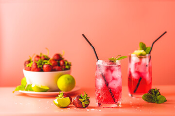 Strawberry mojito cocktail with ice in two glasses with water drops on soft pink color background. Copy space, summer vacation and party concept