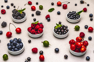 Assorted berries in bowls: bilberry, blueberry, currant, blackberry, cherry and raspberry