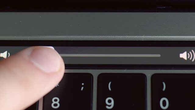 Close up of laptop sensor panel details. Action. Male finger adjusting volume level on the touchpad of a modern computer, technologies concept.