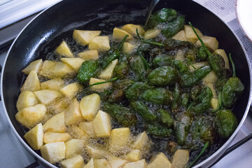 Frying potatoes and peppers in the pan with oil
