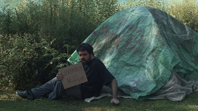 unemployed homeless man next to tarp tent