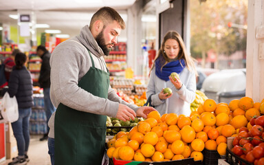 Man seller moving box of oranges in grocery shop. High quality photo