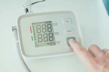 
A person's finger turns on an electronic tonometer to measure blood pressure