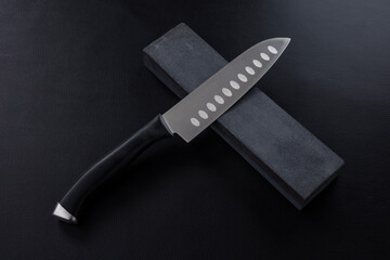 The knife with whetstone on Leather background.