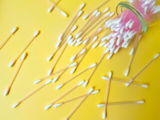 Cotton sticks pink plastic on a yellow background. Personal hygiene and health. Cosmetology and medicine.