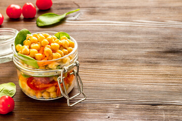 Healthy vegan food. Chickpeas with vegetables in glass jar copy space