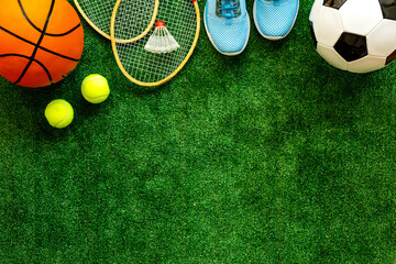Sport games equipment - balls, sneakers, rackets - on grass top view copy space