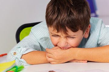 Boy with autism spectrum disorder bite hand and negative expression behavior, close portrait