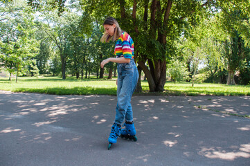 Beautiful teenager girl has fun rollerblading in the park, performs tricks