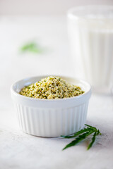 Hemp seeds in a white bowl with a glass of hemp milk.