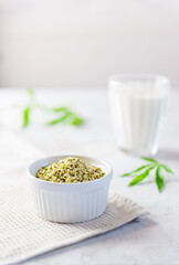 Hemp seeds in a white bowl and a glass of hemp milk. Healthy food, protein.