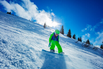 Active boy move fast on snowboard throwing snow around - motion image over blue sky and ski slope...