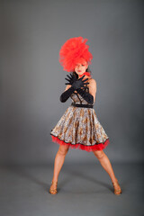 young brunette woman in leopard printed dress and red hat poses on hight heels