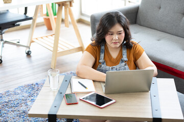 chubby woman looking at laptop computer and thinking about work or study.