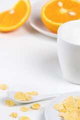 Corn flakes bowl sweeties with milk and orange on white background, close up, fresh and healthy breakfast design concept.