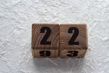 Wooden cubes with numbers on a white crumpled background. 22