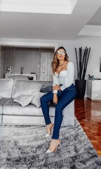 Beautiful model posing for photos in in clear room. Wearing jeans and a white blouse. 