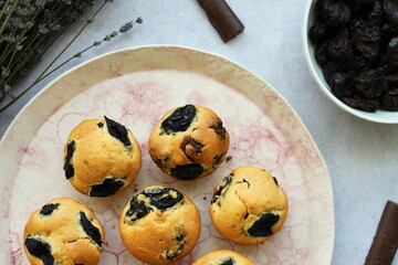 Dried plums muffins with pieces of chocolate inside, served in a handmade rustic ceramic plate. Top view.