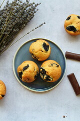 Prunes muffins with chocolate pieces served on a ceramic plate. Top view, vertical photo.