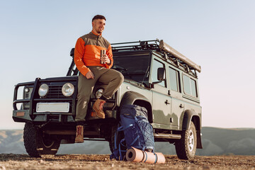 Young man traveler drinking from his thermocup while halt on a hike © fotofabrika