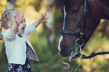 Obraz premium A little girl is happy to see a live horse for the first time