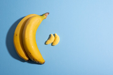 Fruit vs candy. Yellow bananas over blue with copy space, design, comparing. Healthy eating concept. Spanish, European Union agricultural product. Geographical Indication. Children dessert © kepazuria