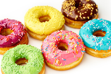 Sweet colorful glazed doughnuts from above on white background. Junk food top view, sugar treat