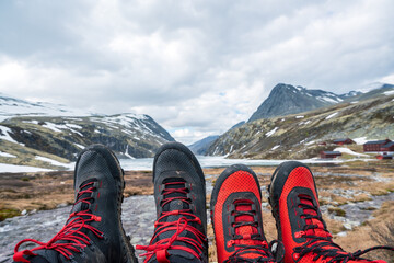 Black and red mountain hiking boots towards mountain scenery in Norway.