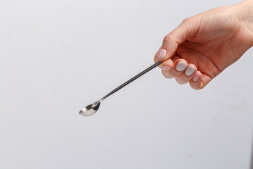 A woman's hand holds a coffee spoon. white background