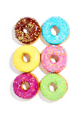 Fototapeta premium Sweet colorful glazed doughnuts from above on white background. Junk food top view, sugar treat