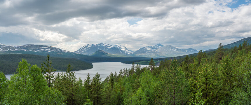 Panorama shot of Rondane national park and mountain peaks from Sohlbergsplassen viewpoint. Forest and Atne river in the foreground.