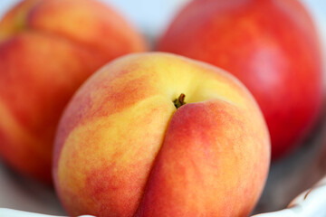 Fototapeta na wymiar Ripe red-yellow bright peaches lie on a white plate. Healthy eating. Fruit diet. macro shooting
