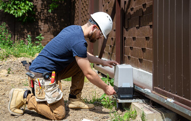 Electrician Builder at work, servicing the fuselage industrial switchboard. Professional in overalls with an electrician's tool.
