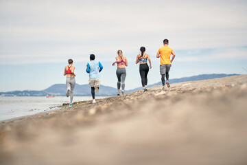 Group of young people running and exercising on the beach.