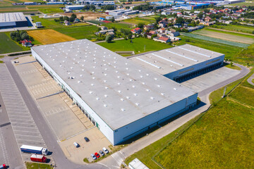 Aerial view of goods warehouse. Logistics center in industrial city zone from above. Aerial view of trucks loading at logistic center. View from drone.