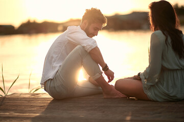 Fototapeta premium Couple in love having romantic tender moments on the river at sunset.