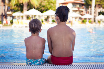 Two brothers are resting in the pool in summer
