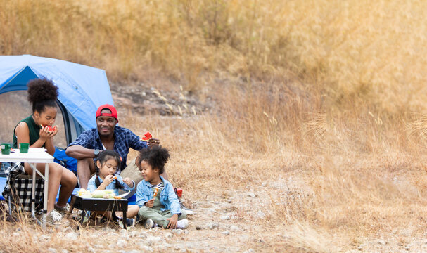 Family Enjoying Camping Holiday. Family interacting while having fruit and solf drink outside the tent at campsite