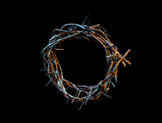 The crown of thorns lie on an isolated black background, with a blue tint of light. The concept of Holy week, associated with suffering and love.