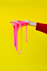 The toy for children mucus and liquid flowing on hand on a yellow background